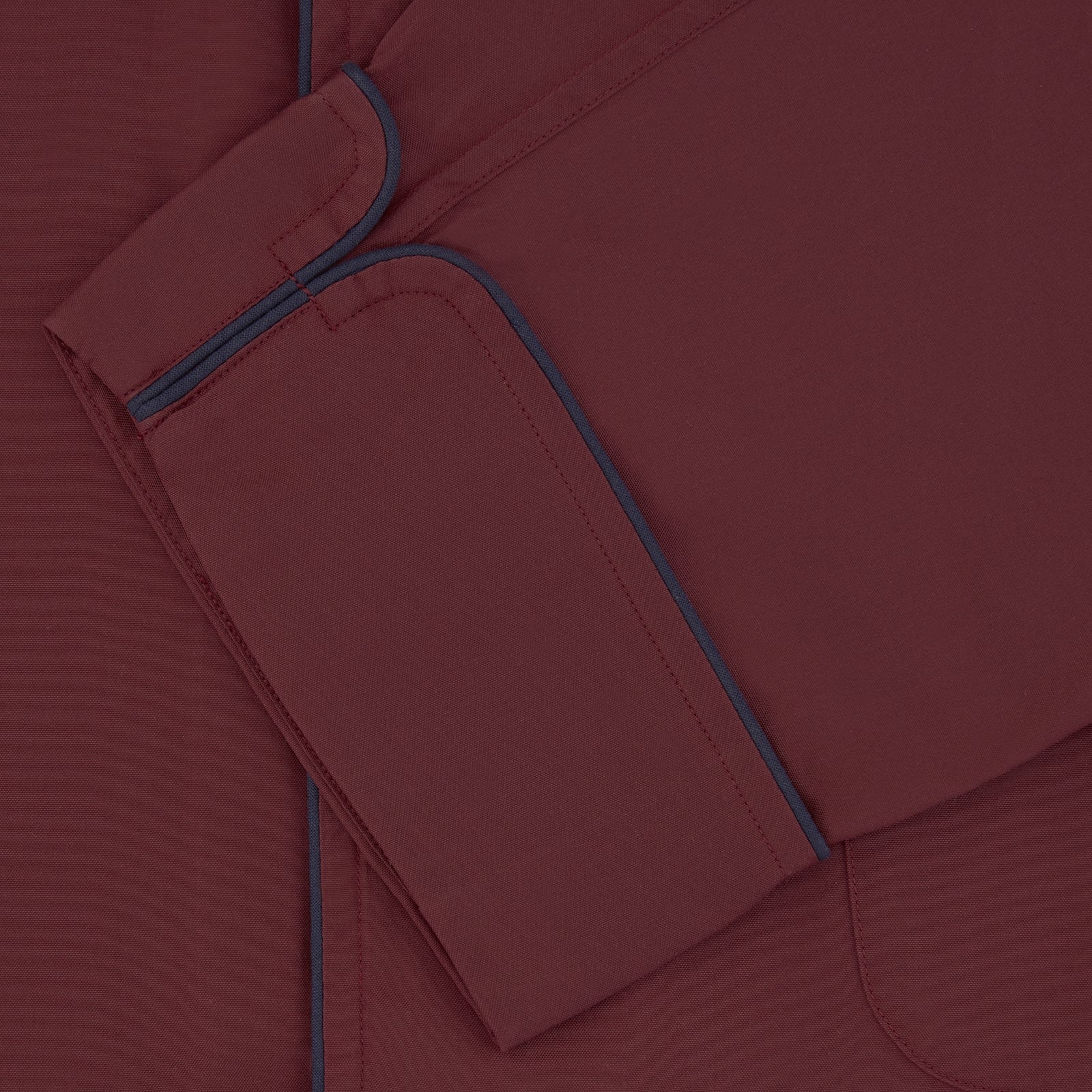 View 4 of product The Wine Piped Silk Pyjama Set by Turnbull & Asser features a folded maroon top with white buttons and dark trim, displayed beside a matching sleep mask with tie straps, set against a plain white background.