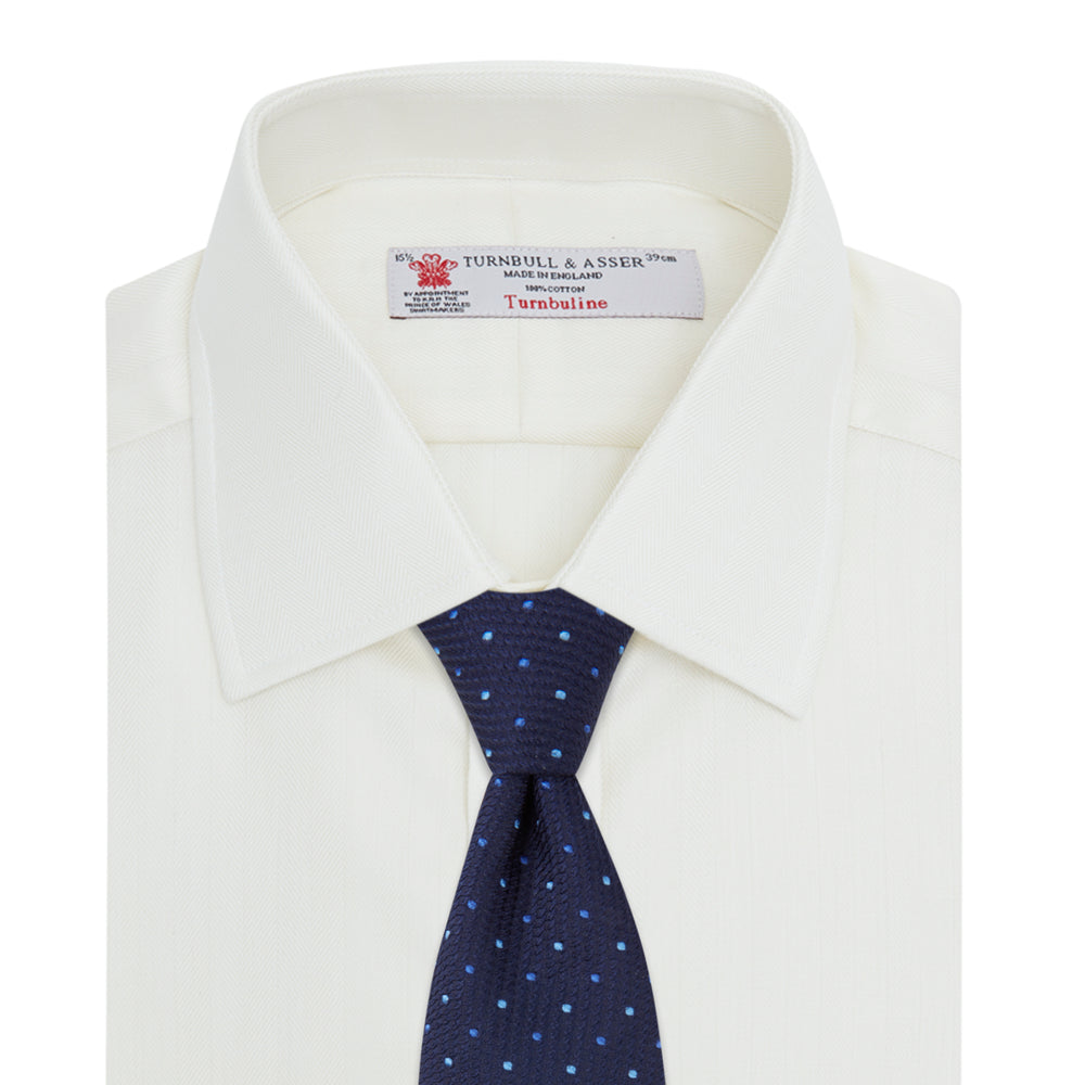 The Turnbull & Asser Cream Herringbone Superfine Cotton Shirt features a T&A collar, double cuffs, and a subtle pattern. It is neatly folded with white buttons and displayed on a plain white background.