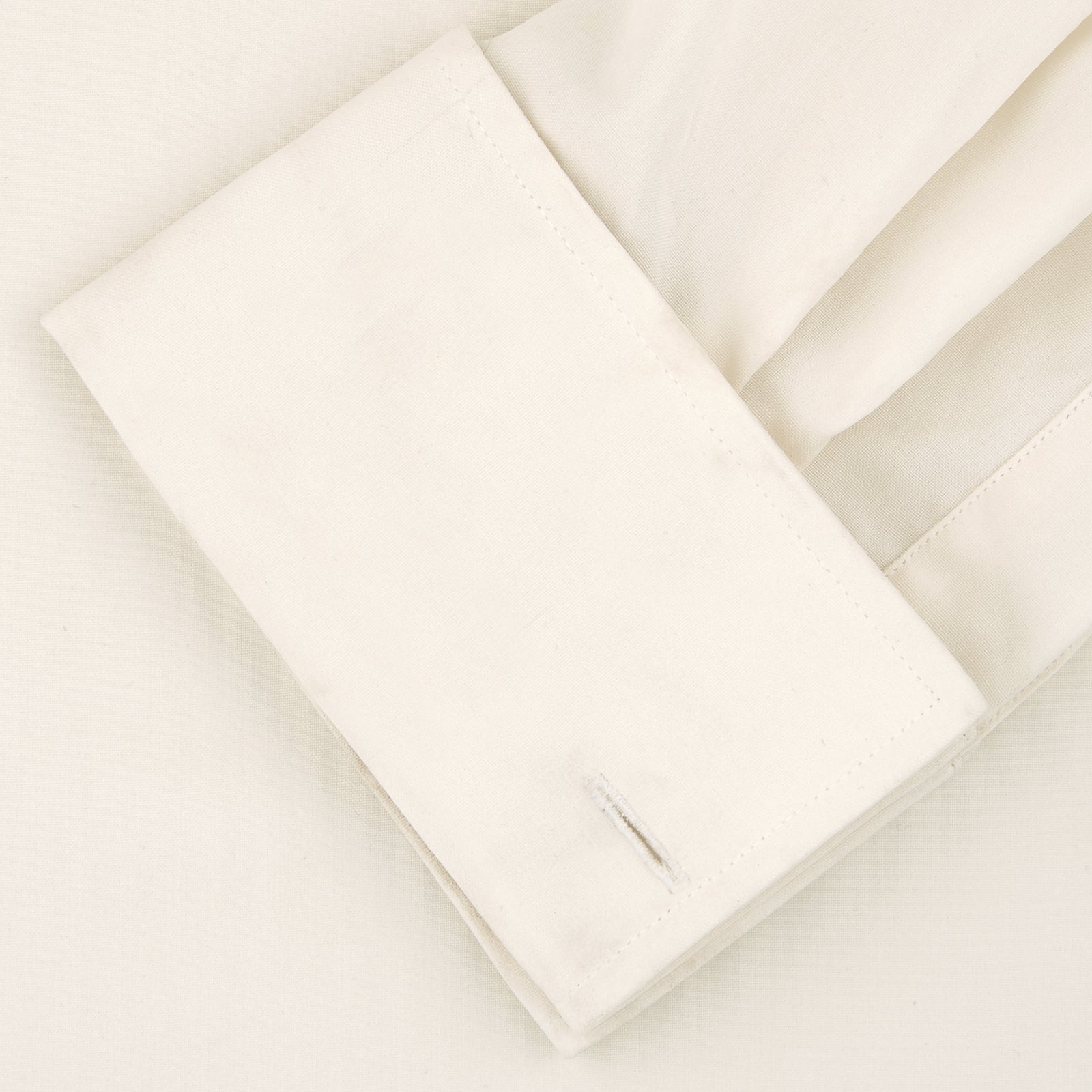 View 6 of product The Turnbull & Asser Tailored Fit Cream Pleated Front Silk Dress Shirt with T&A collar and double cuffs is displayed neatly folded against a light gray background.