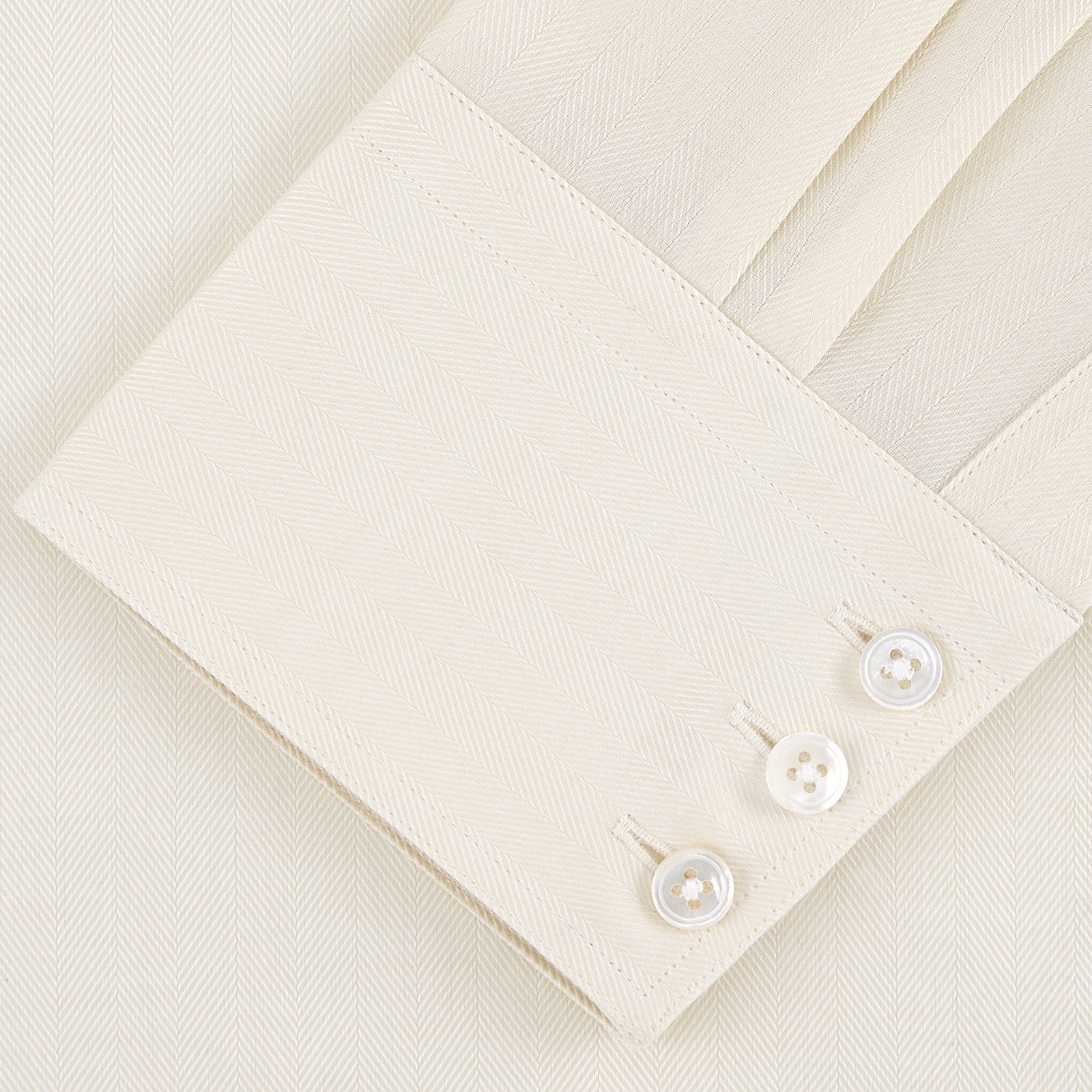 View 4 of product The Turnbull & Asser Weekend Fit Cream Herringbone Western Shirt features a Norfolk collar, button cuffs, and chest pockets, elegantly folded and displayed on a plain white background.