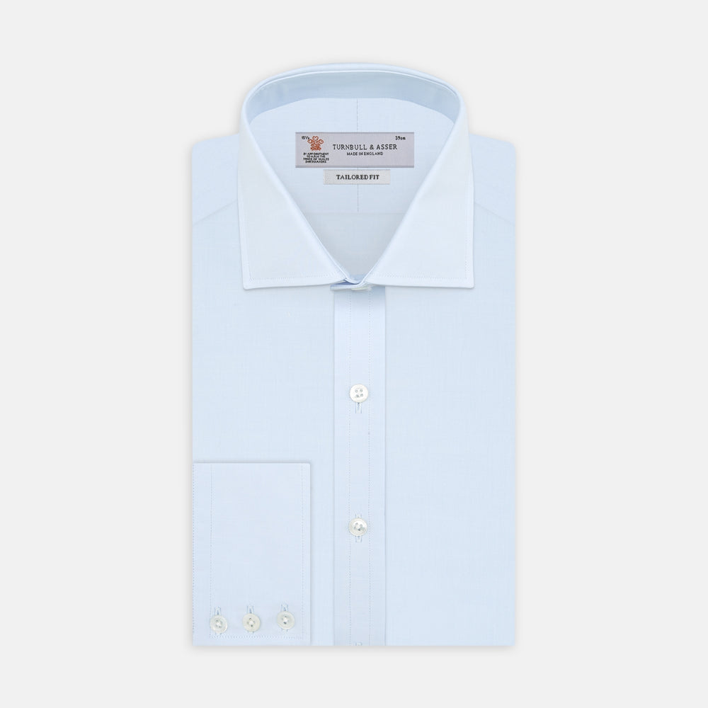 A neatly folded Turnbull & Asser Tailored Fit Two-Fold 120 Light Blue Shirt with a Kent collar and 3-button cuffs is displayed against a plain light gray background.
