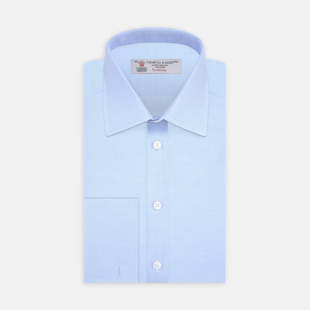 The Turnbull & Asser Light Blue Herringbone Superfine Cotton Shirt features a T&A collar, double cuffs, and is neatly folded against a plain white background.
