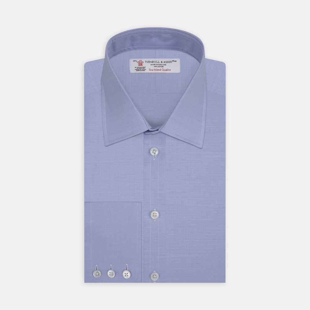 The Blue Herringbone Sea Island Quality Cotton Shirt by Turnbull & Asser features a T&A collar, 3-button cuffs, and is crafted from luxurious cotton. The shirt is displayed neatly folded on a plain white background.