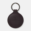View 1 of product The Violla Leather Key Fob by Turnbull & Asser is a round, dark brown leather accessory with embossed branding, visible edge stitching, and a metal loop at the top. Made in England, it combines elegance and function for your keys.