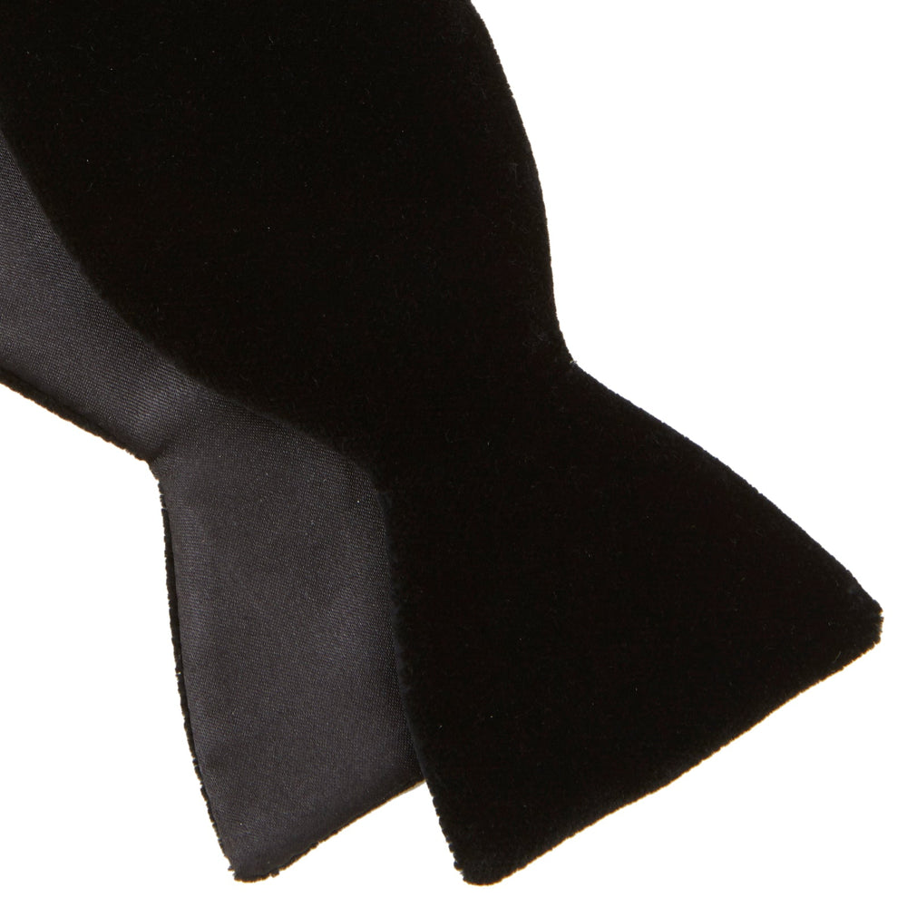 The Turnbull & Asser Black Velvet Bow Tie, shown against a plain white background, is an elegant choice for formal occasions.