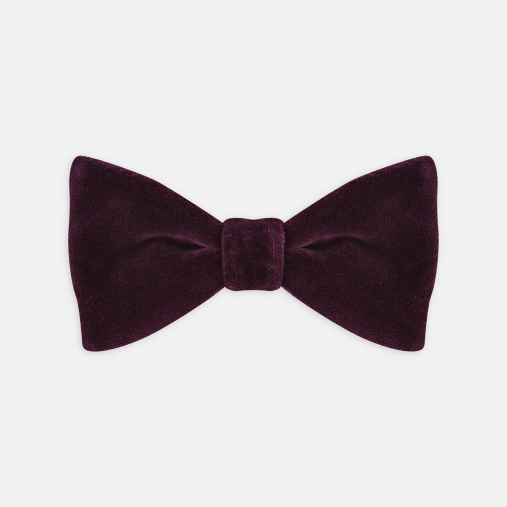 The Turnbull & Asser Purple Velvet Bow Tie is showcased on a plain white background, offering an elegant accessory to elevate any formal outfit with sophistication.