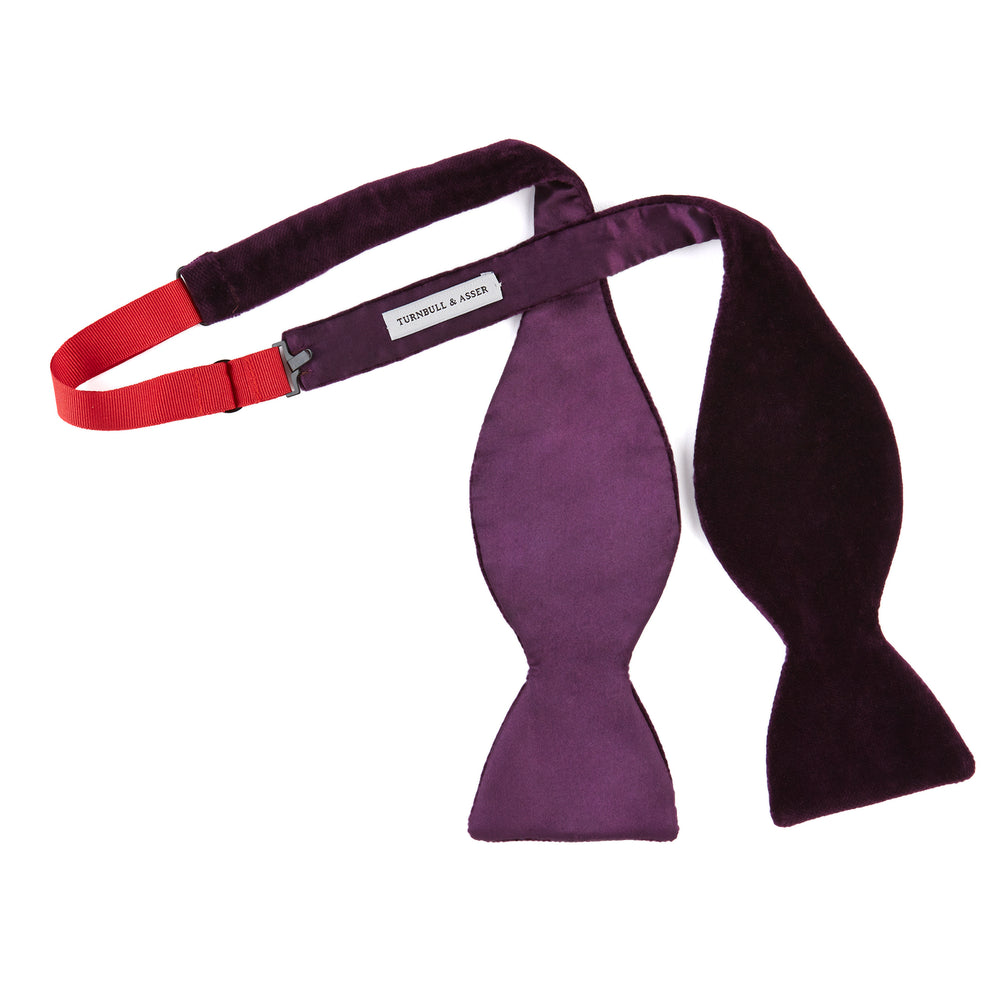 The Turnbull & Asser Purple Velvet Bow Tie is showcased on a plain white background, offering an elegant accessory to elevate any formal outfit with sophistication.