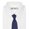 View 2 of product The Turnbull & Asser Slim Navy & White Spot Herringbone Silk Tie features a subtle texture and white polka dots, making it a refined men's accessory. Shown rolled-up on a plain white background.